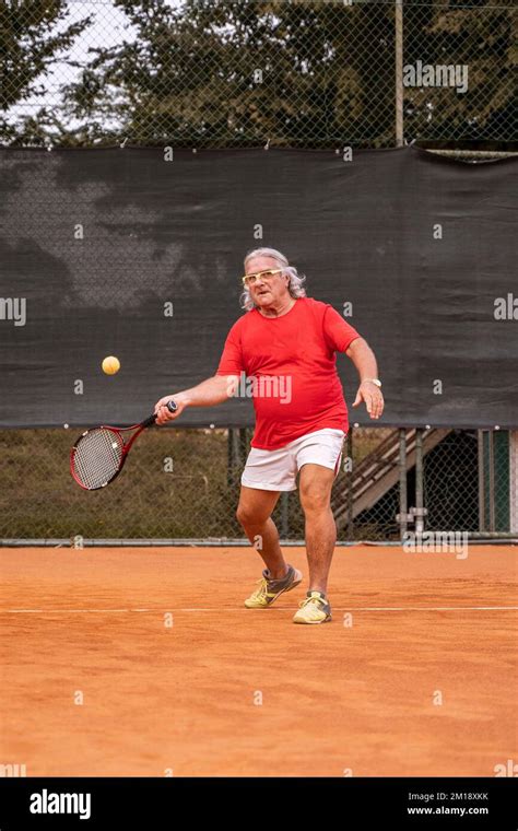 Senior Tennis Player Dressed In Sportswear In Action On A Clay Tennis