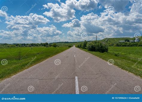 Two Lane Countryside Road Among Green Fields And Meadows Stock Photo