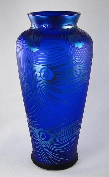 A Blue Vase With A Peacock Design On The Front And Bottom Sitting On A White Surface