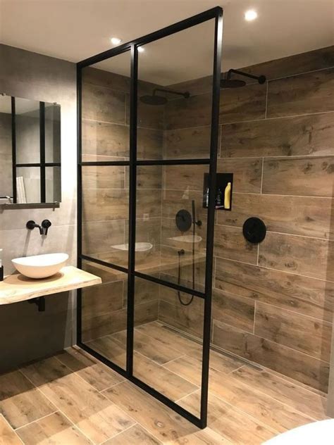 Master ensuite features a black vanity with modern brushed gold pulls, white quartz counter top, brushed gold faucets, aged gold brass wall sconces, black framed rectangular mirrors against a ceramic tile wood design wall. 25 Trendy Wood Look Tile Ideas For Bathrooms - DigsDigs