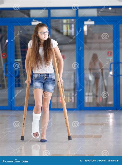 A Young Girl Is On Crutches In The Corridor Of The Hospital Stock Image