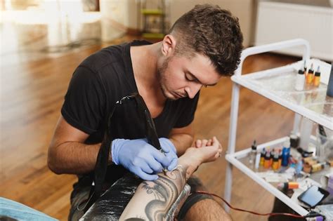 Un Tatuatore Professionista Che Fa Un Tatuaggio Sul Braccio Di Un Giovane A Macchina Con