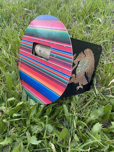 a multicolored wooden box sitting in the grass with a bird painted on it