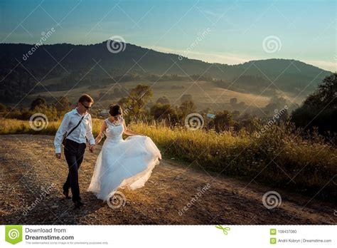 Walking Newlywed Couple Along The Road During The Sunset Handsome