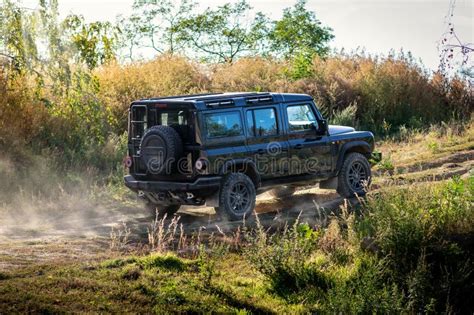 The Rugged Off Road Car Drives Through The Countryside On A Dirt Road