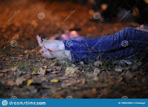 Find the perfect dead woman feet stock photo. Bare Woman Feet, Legs In Jeans, Lying On The Ground Among Dead Leaves, Light From A Burning Fire ...