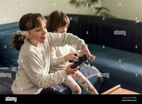 Two Happy Girls Playing Video Games Playstation At Home Stock Photo