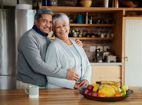 Portrait Of Happily Retired Elderly Biracial Couple Standing Hugging And Smiling At Camera