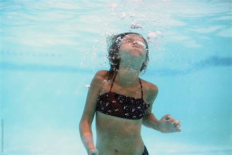 A Girl Holding Her Breath While Swimming Underwater By Stocksy