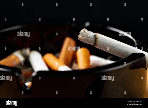 Burning Cigarette In A Black Ash Tray Stock Photo Alamy