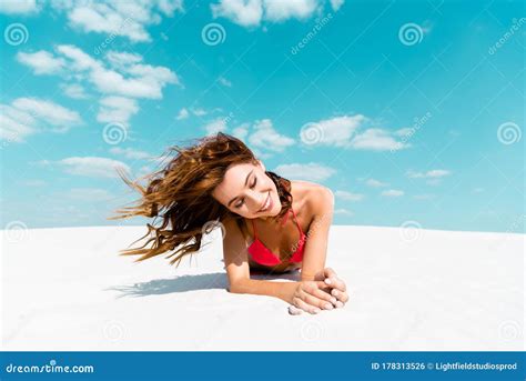 beautiful girl in swimsuit lying on sandy beach with blue sky and clouds at background stock