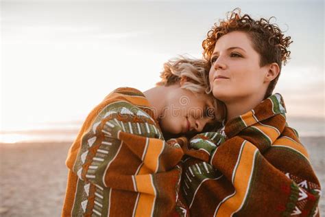 content lesbian couple wrapped in a blanket at the beach stock image