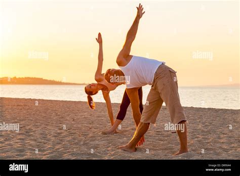 People Practising Yoga On Beach Bending Over Stock Photo Alamy