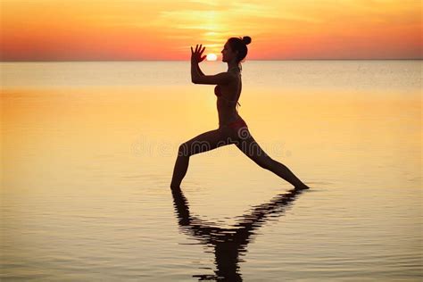 Young Beautiful Brunette Woman Doing Yoga At Sunset On Beach Stock