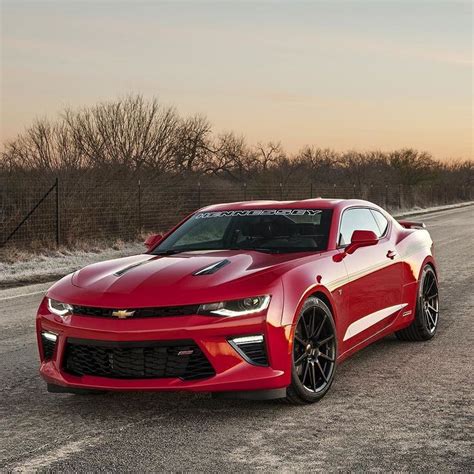 A Red Chevrolet Camaro Driving Down The Road