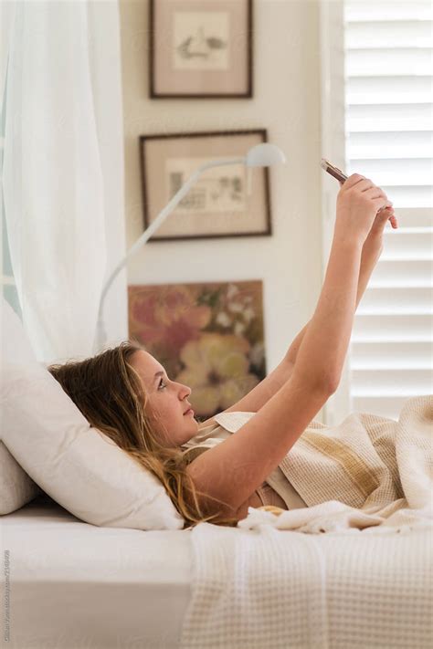Teen Girl Using Her Phone In Her Bedroom Del Colaborador De Stocksy