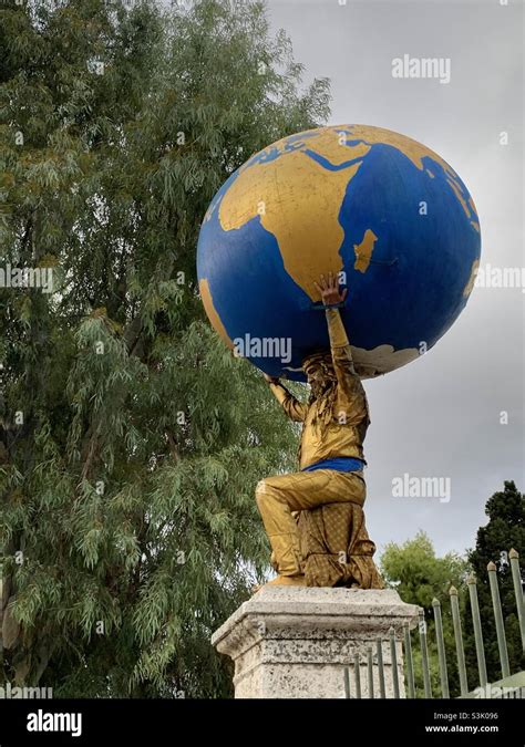 Man Posing As A Statue Holding The World In Gold In Athens Greece Stock