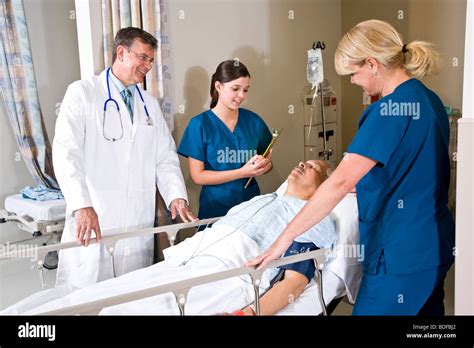 Doctor And Nurses In Hospital Recovery Room With Patient Stock Photo