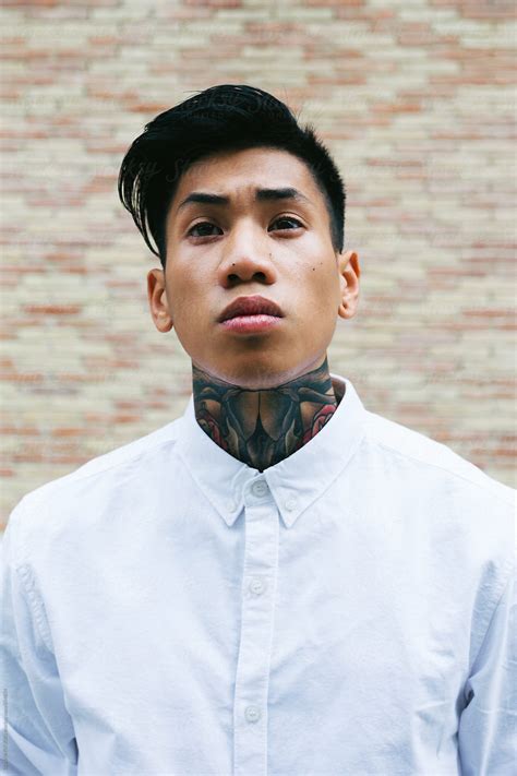 Portrait Of A Young Asian Man With Tattooed Neck Standing In Front Of A