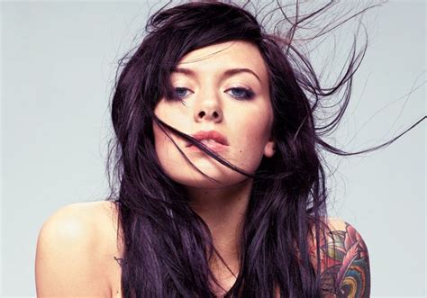 A Woman With Long Black Hair And Tattoos On Her Body Is Posing For The