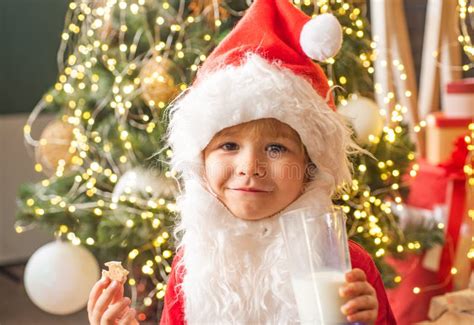 Happy Santa Claus Eating A Cookie And Drinking Glass Of Milk At Home