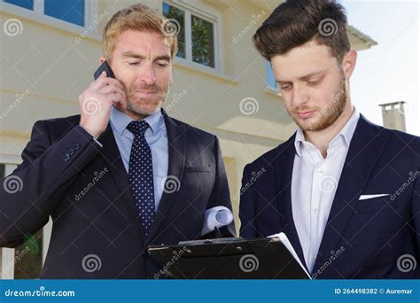 Suited Men With Clipboard And Smartphone Outside Residential Property