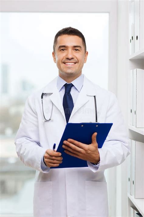 Happy Doctor With Clipboard In Medical Office Stock Photo Image Of
