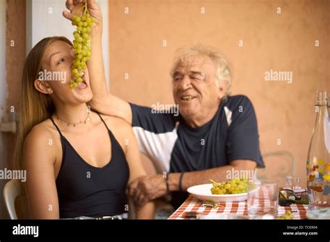 Old Senior Man Feeding Young Woman With Wine Grapes Sharing Greek