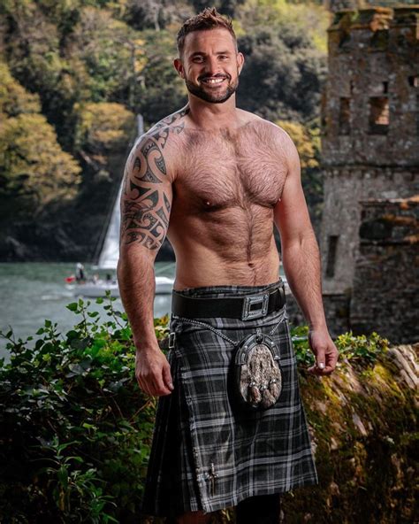 A Man Wearing A Kilt Standing In Front Of A Lake