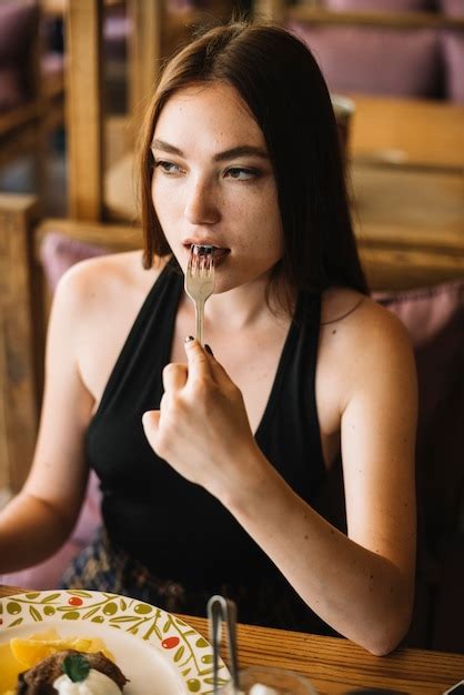 포크로 디저트를 먹는 젊은 여자의 근접 촬영 무료 사진