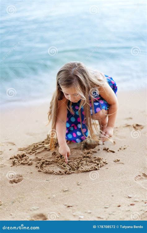 A Little Girl Plays In The Sand Near The Water Stock Photo Image Of