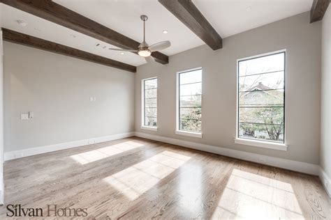 Desk lamp on a small table and a simple, wooden cabinet in an empty living room interior with white wall and place for a sofa. modern, spacious game room with exposed wood beams (photo ...