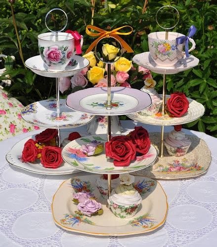 Three Tiered Trays With Roses On Them Sitting On A Table In Front Of