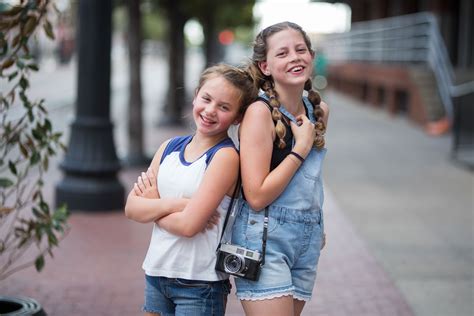 Two Tween Girls Laughing Together On City Sidewalk Camera Kristina