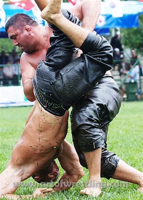 Two Men Are Wrestling In The Mud At An Outdoor Event One Is Wearing
