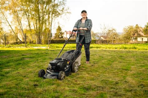 Mowing Or Cutting The Long Grass With A Green Lawn Mower In The Summer