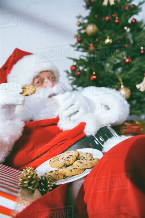 Selective Focus Of Santa Claus Eating Cookies And Drinking