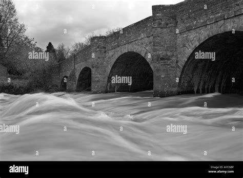 River Water Rushing Under The Arches Of An Old Stone Bridge Stock Photo