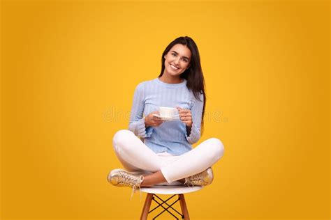 Smiling Hispanic Lady Drinking Coffee In Bright Yellow Studio Stock