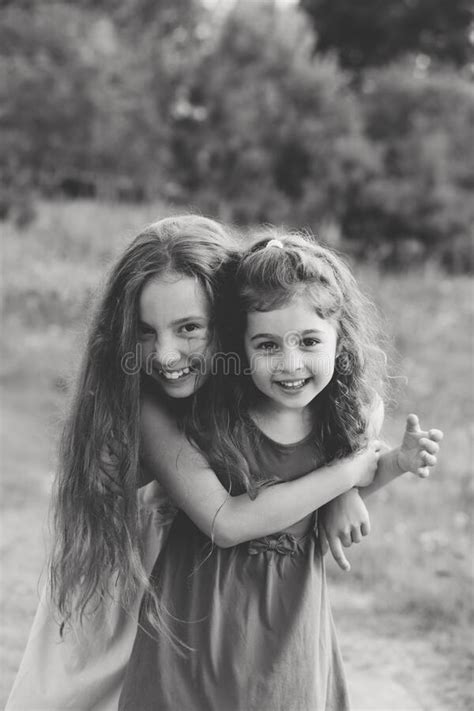 Black And White Portrait Of Two Happy Little Girls Laughing And Hugging