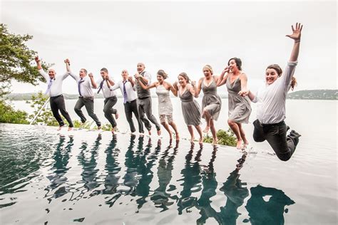 A Group Of People Jumping Into The Air In Front Of A Body Of Water With