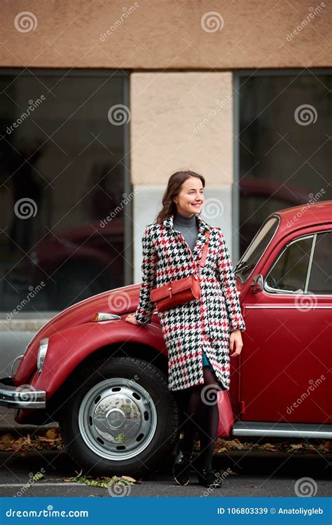 Brunette Woman Leaning On Red Retro Car Looking At Distance Stock