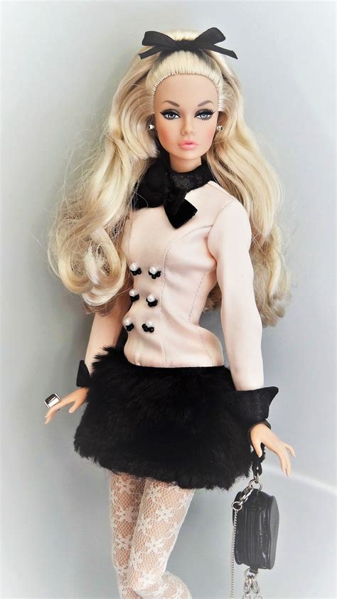 a barbie doll wearing a black and white outfit holding a handbag in her right hand