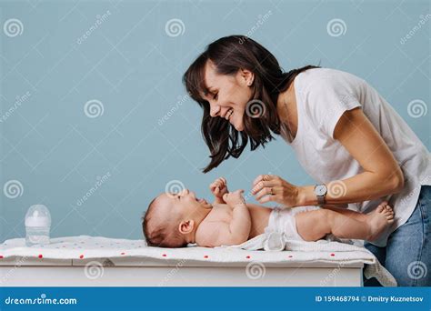 Mother Changing Diaper On Her Baby On Table Over Blue Background Stock