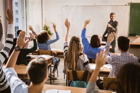 Back View Of High School Students Raising Hands On A Class