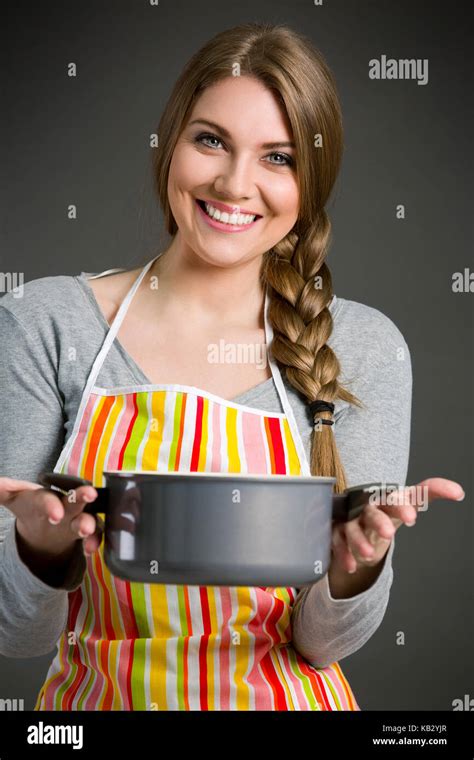 Portrait Of Cheerful Housewife In Apron Holding Saucepan Stock Photo