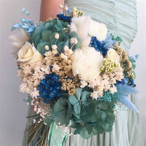A Woman In A Green Dress Holding A Blue And White Wedding Bouquet With