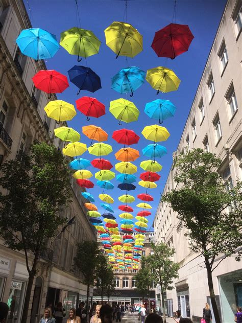 Many Colorful Umbrellas Are Suspended From The Sky Above A City Street