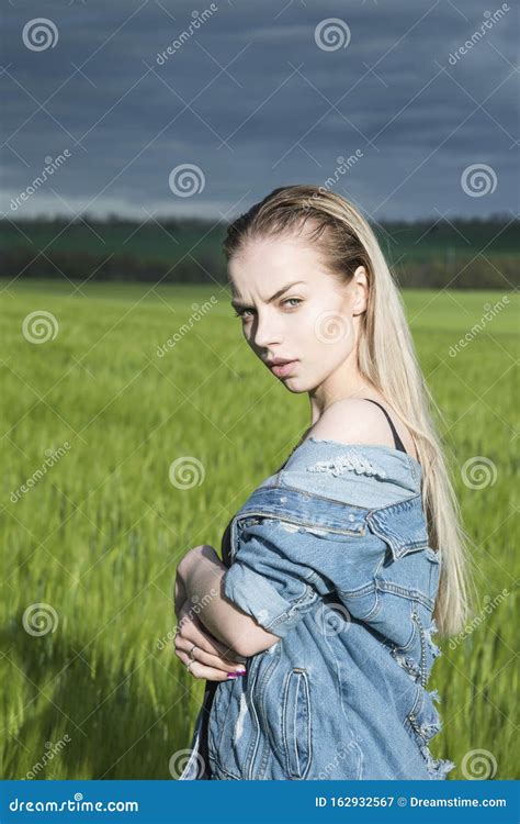 Beautiful Blonde Girl Is Standing In A Field Against A Background Of Clouds Stock Image Image