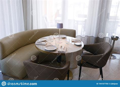 Casual Dining Table Set Up With Sofas Chair And Cutlery Sets Stock